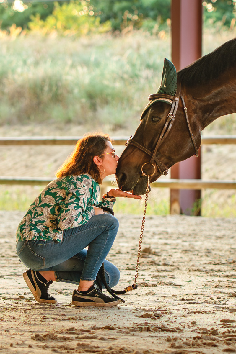 Une cavalière dans un manège avec son cheval pour une séance photo