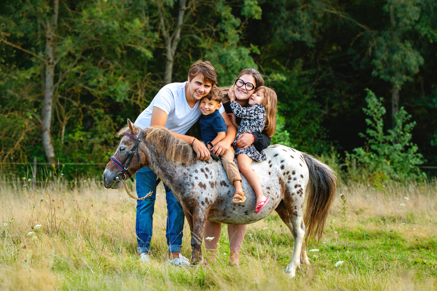 Une famille en séance photo en famille avec leur poney dans un champs à Colomiers