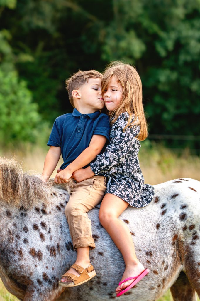 Un petit garçon qui fait un bisou à sa soeur sur la joue sur leur poney à Saint-Lys