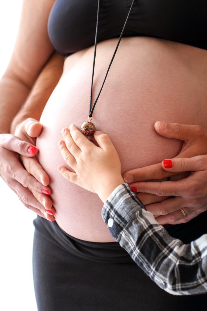 Les mains de toute la famille sur le ventre de la maman en séance photo grossesse à Plaisance du Touch