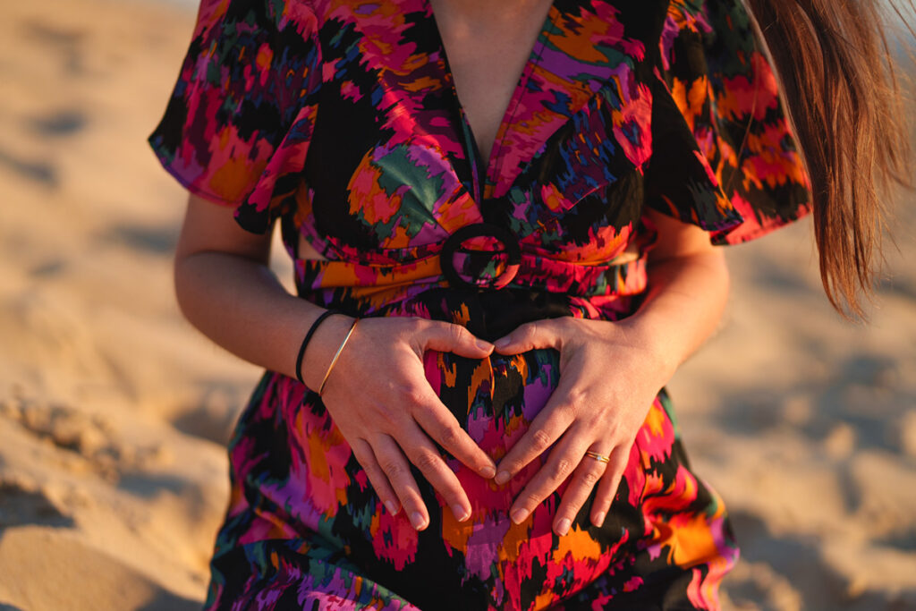 Une femme enceinte qui fait un coeur avec ses mains sur son ventre