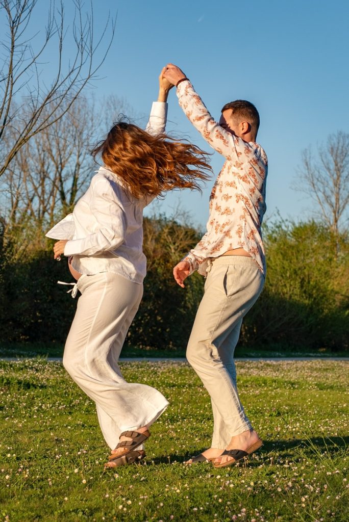 Un couple qui danse main dans la main en séance grossesse à Toulouse