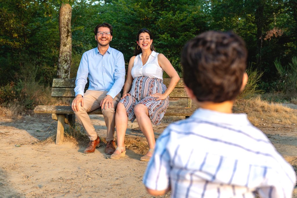 Deux parents rigolant joyeusement en regardant leur fils faire une grimace de dos en séance photo à Blagnac