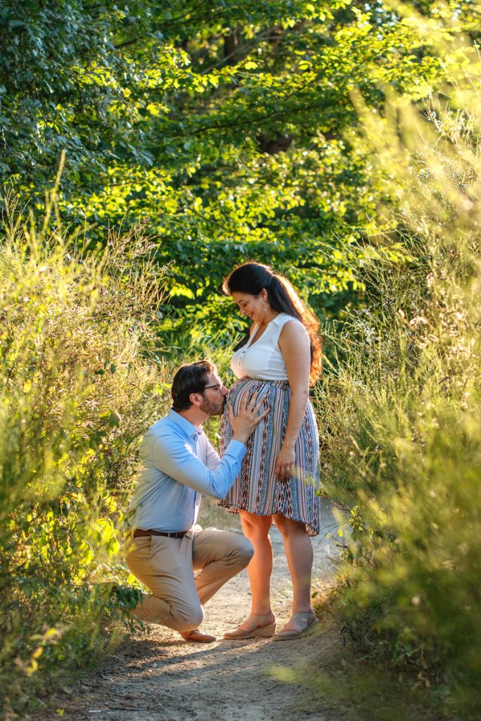 Un homme qui embrasse le ventre de sa femme enceinte en séance photo grossesse à Fonsorbes