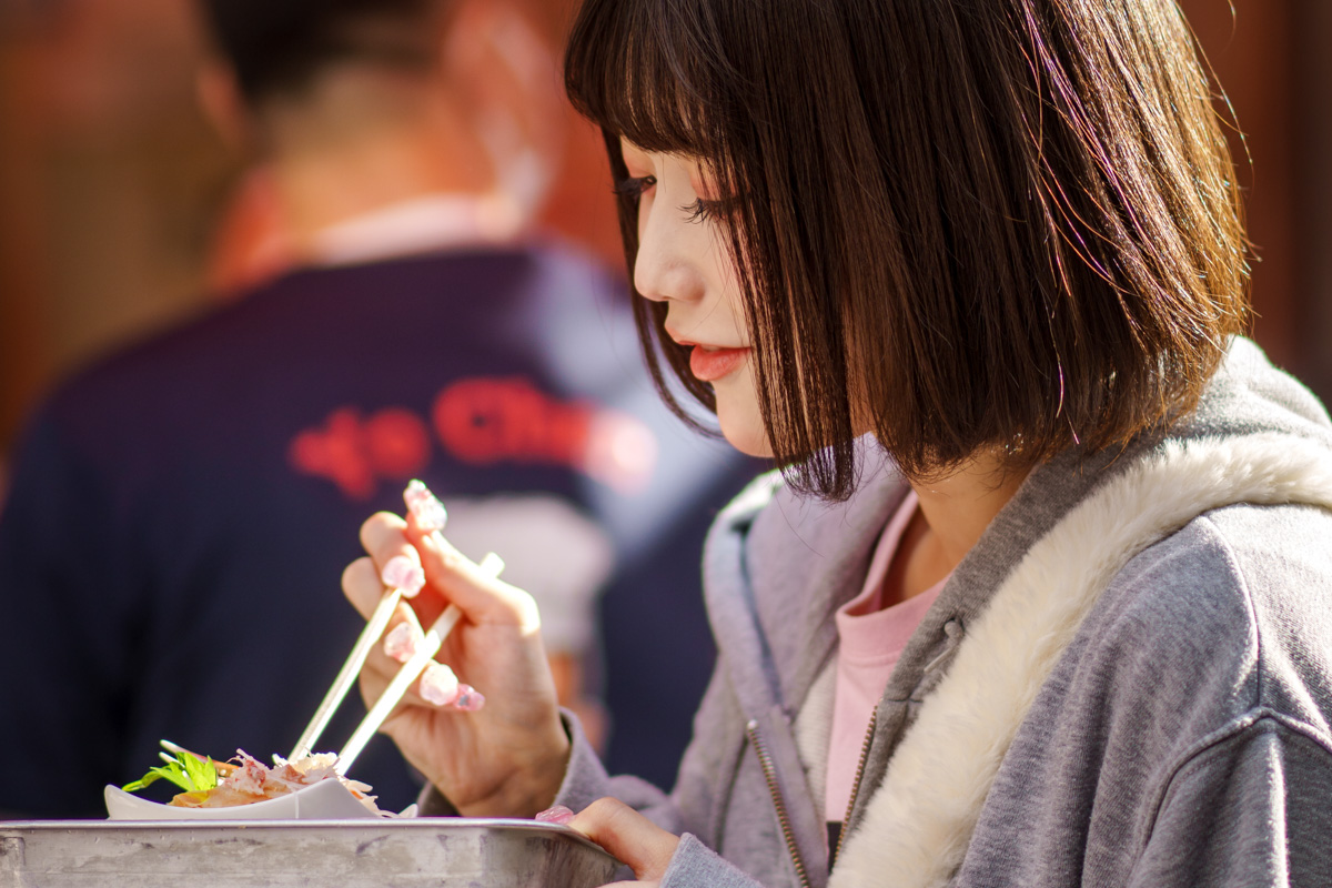 Fille dégustant un plat dans les rues animées de Tokyo, Japon