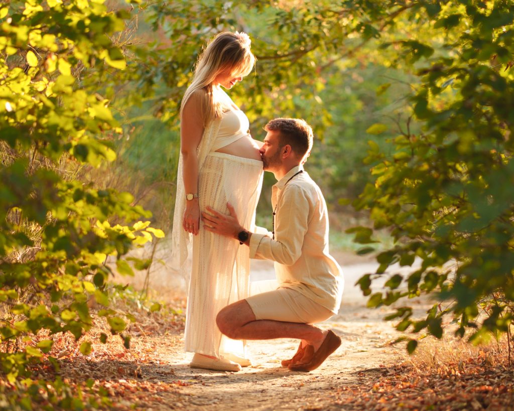 Séance photo grossesse : papa embrassant le ventre de maman au coucher du soleil, moment tendre et lumineux à Colomiers