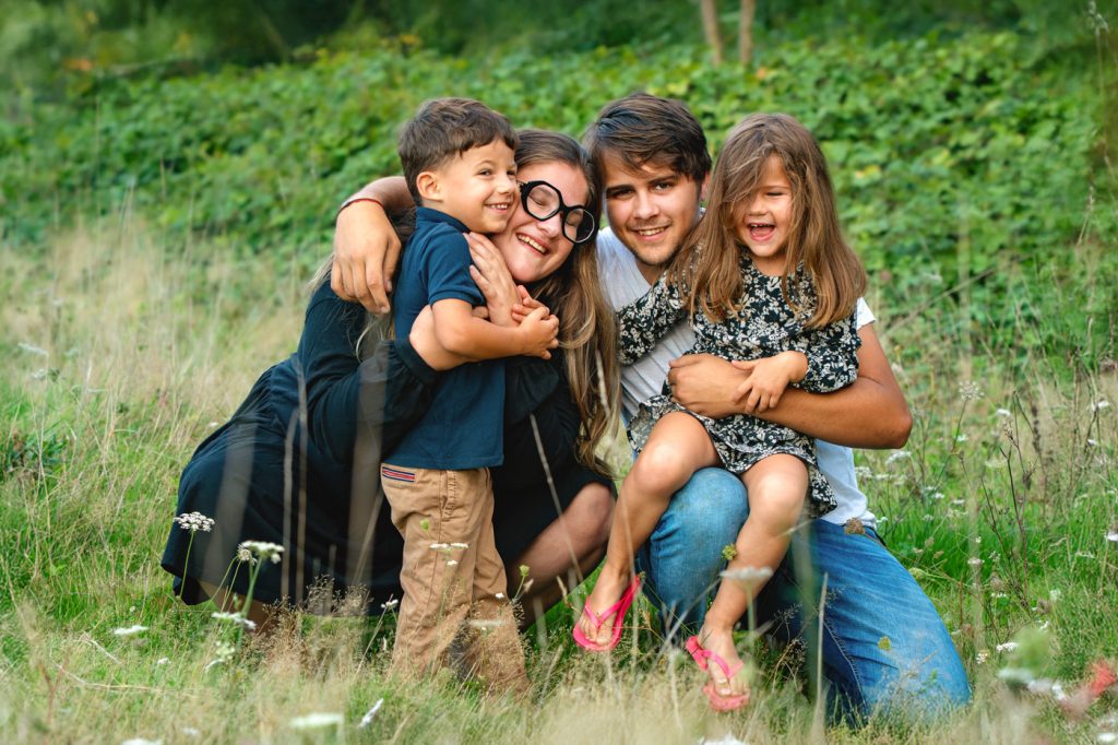 Une famille qui fait un câlin collectif en souriant lors de séances photo famille à Tournefeuille