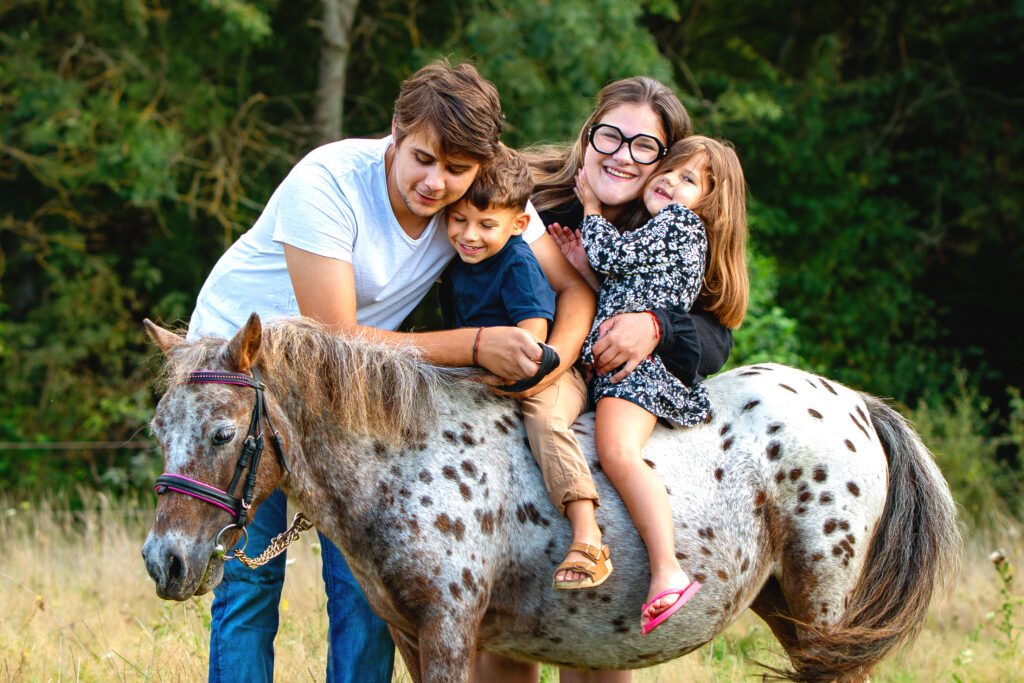 Une famille joyeuse en séance photo avec leur poney à Saint-Lys