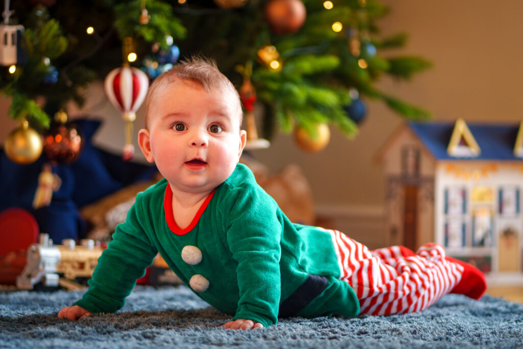 Un bébé habillé en lutin de Noel devant le sapin à Blagnac