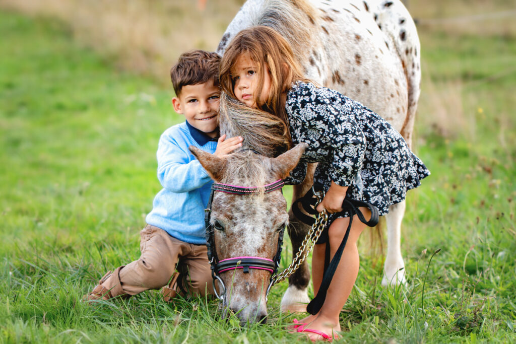 Deux enfants qui font un câlin à leur poney en séance photo famille