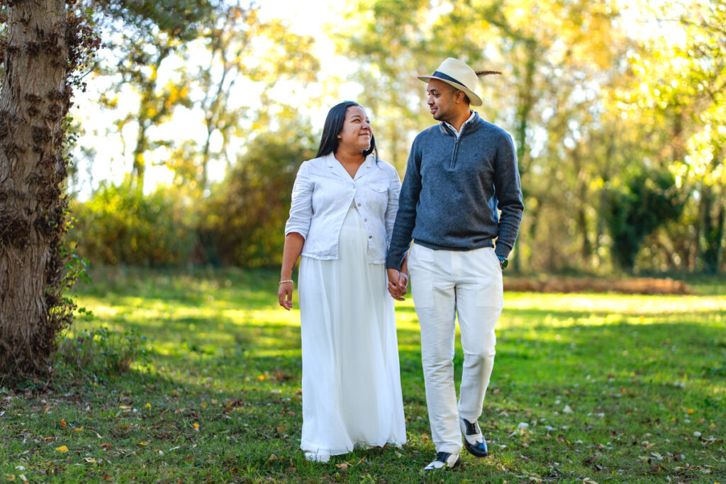 Un couple qui marche main dans la main en séance photo grossesse