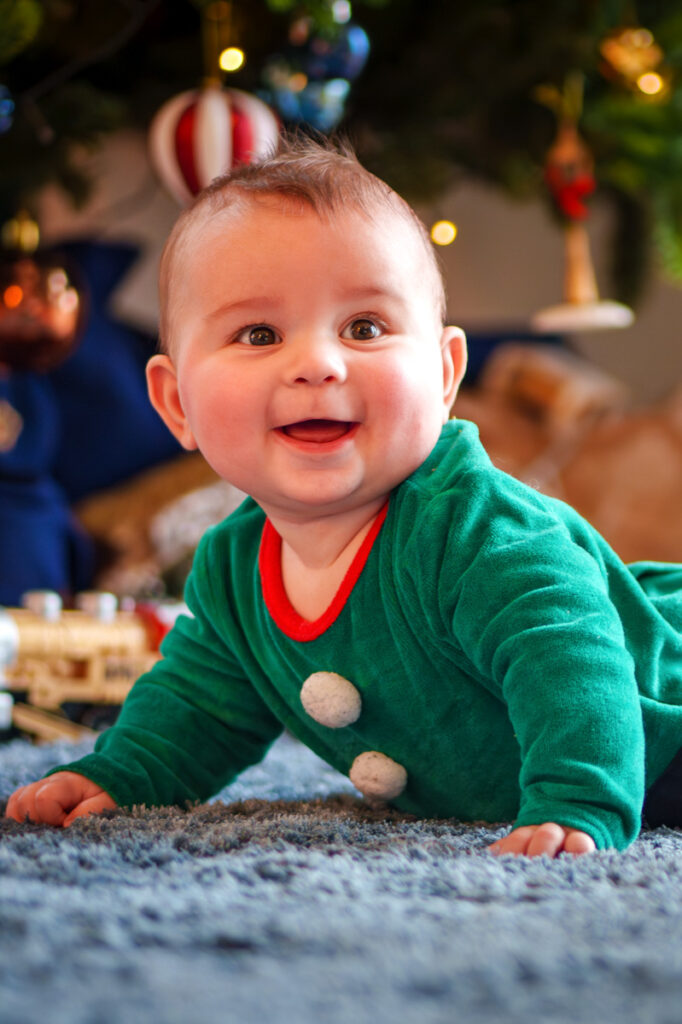 bébé souriant sous le sapin de Noel - séance photo famille