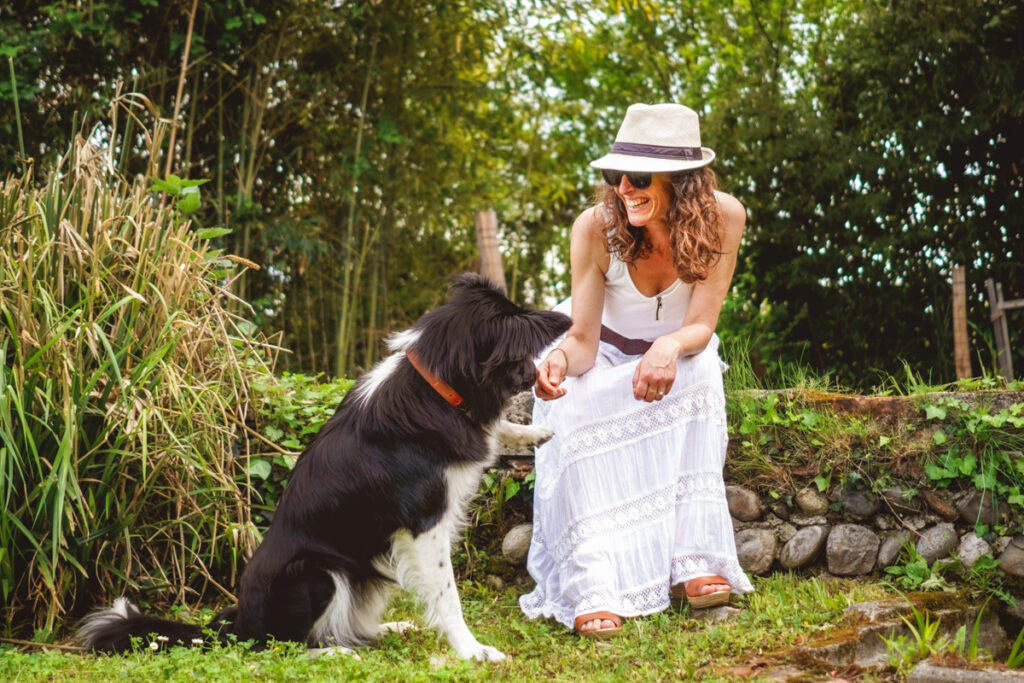 Une femme souriante qui demande à son chien de lui donner la patte - séance photo animaux