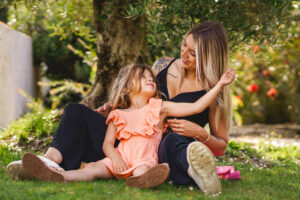 Une mère et sa fille jouant assises au pied d'un olivier - séance photo famille