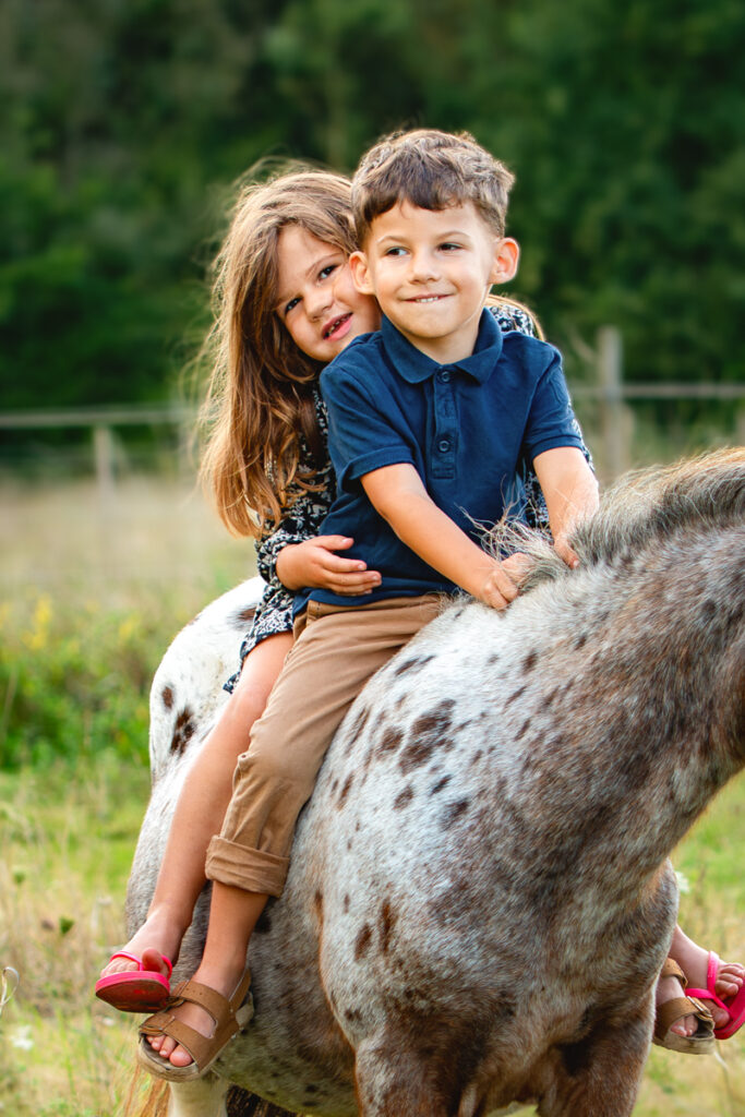 deux enfants heureux sur leur poney - séance photo famille