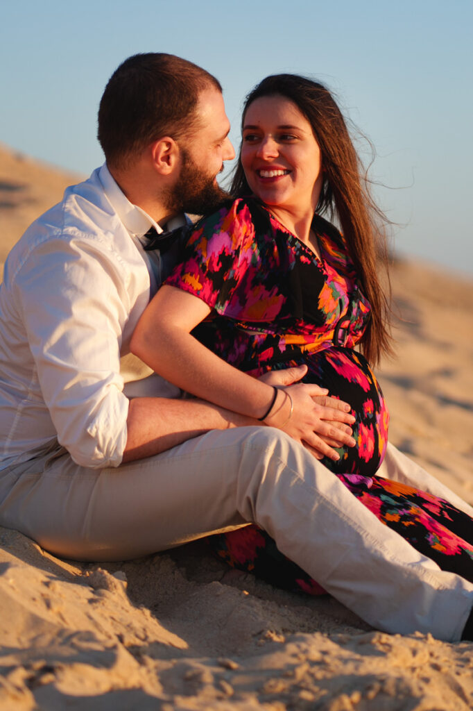 couple à la plage à l'océan échangeant un regard amoureux - séance photo grossesse