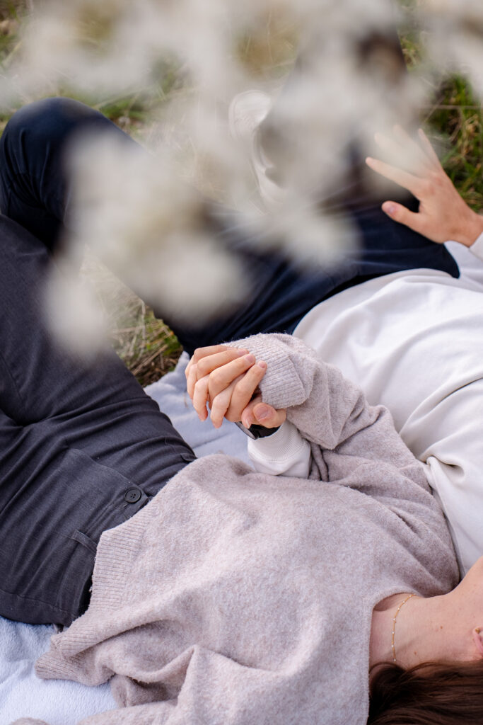 les mains enlacées d'un couple sous les cerisiers en fleurs en séance photo de printemps à Toulouse
