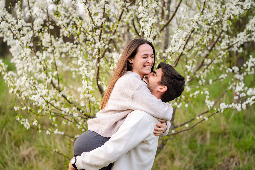 Un couple qui s'enlace et rigole sous un cerisier en fleurs lors d'une séance photo de couple au printemps à Toulouse