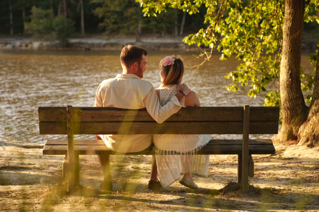 Un couple de dos assis sur un banc au coucher du soleil face à un lac à Toulouse
