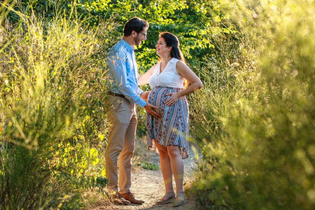 Un couple se regardant amoureusement dans les yeux en forêt - séance grossesse à Toulouse