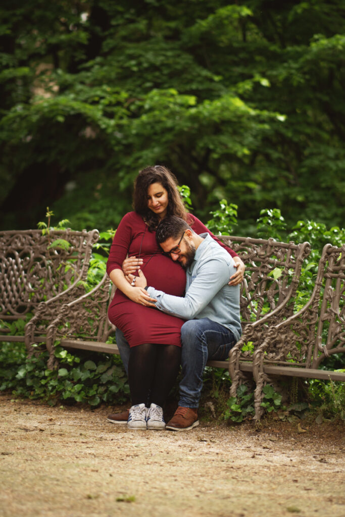 Un couple assis sur un banc dans un parc pour des photos de grossesse - Où faire sa séance photo à Toulouse