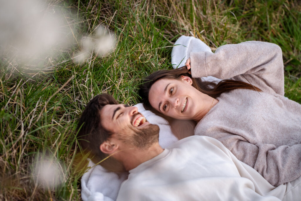 Un couple allongé dans l'herbe sous un cerisier en fleur en séance photo de couple à Tournefeuille